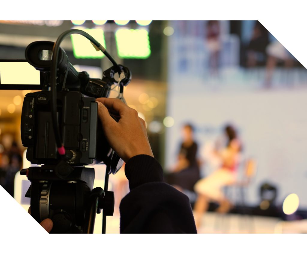 Presenter speaking to a camera during a live online broadcast with production equipment visible, representing virtual and hybrid events, livestreaming, and remote audience engagement services.