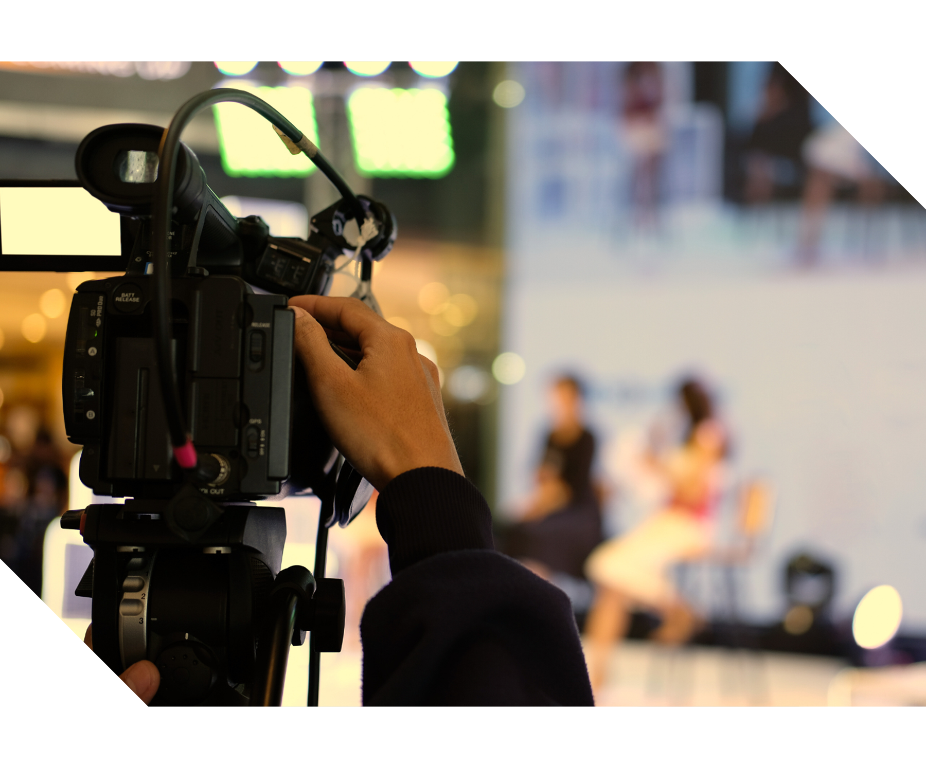 Presenter speaking to a camera during a live online broadcast with production equipment visible, representing virtual and hybrid events, livestreaming, and remote audience engagement services.